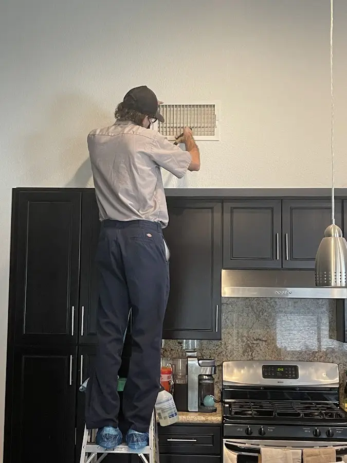 Technician inspecting an air vent during HVAC service in Crouch Mesa